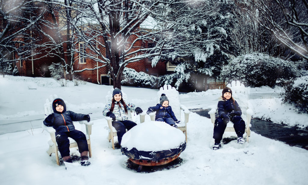 kids sitting in Adirondack chairs in the snow