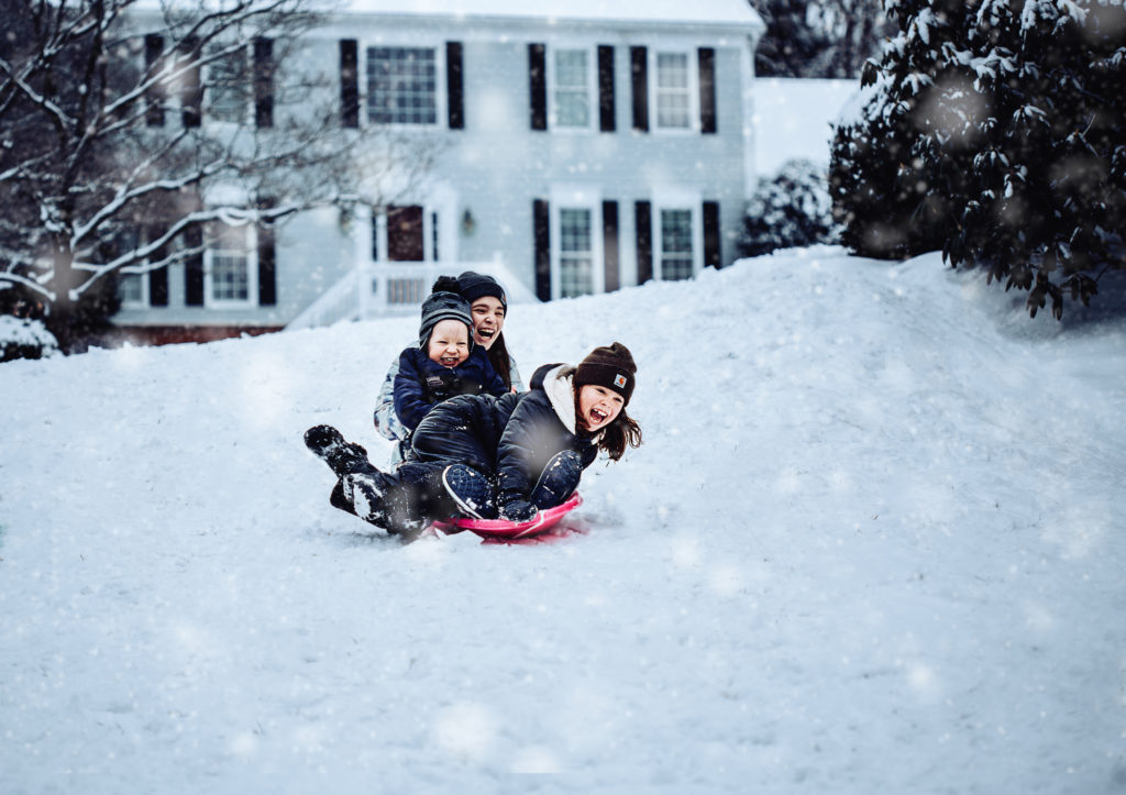 three kids sledding down a hill in the snow in Vienna Virginia